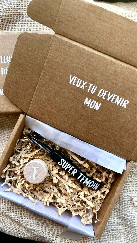 Coffret demande témoin personnalisé avec écriture "Veux-tu devenir mon super témoin" et accessoires à l'intérieur.